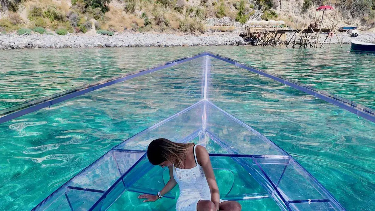 Clear-bottom boat with visible seabed sailing from Ischia Porto toward the Green Cave on an Ischia clear boat tour, Campania, Italy